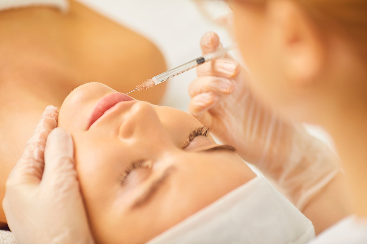 Cosmetology doctor makes beauty injections in the lip to a woman.