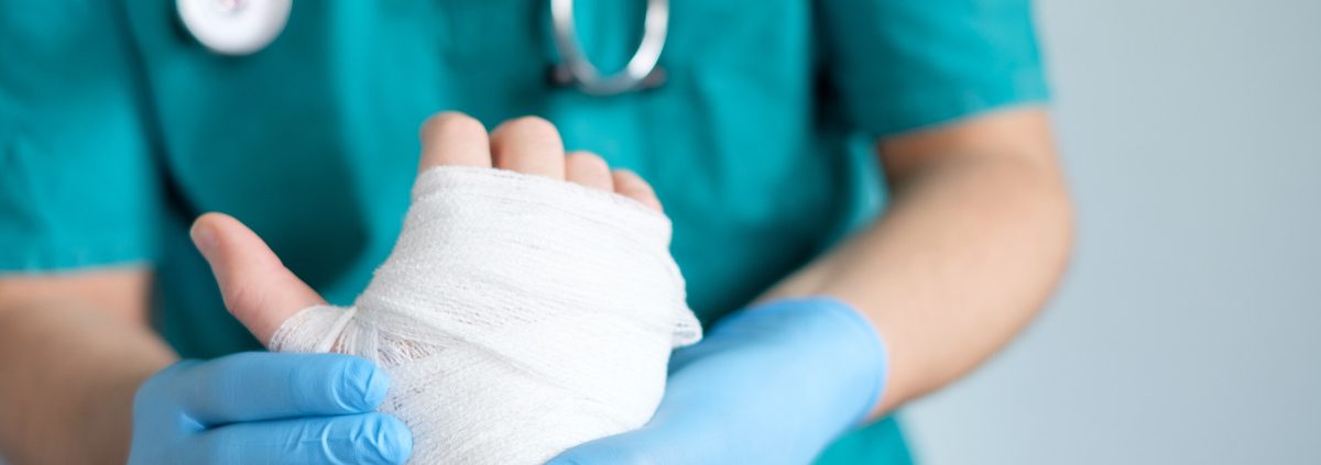 close up of doctor bandaging one hand after an accident