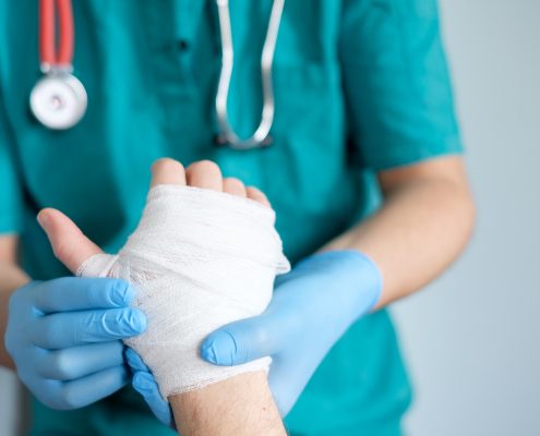close up of doctor bandaging one hand after an accident