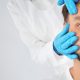 Doctor examining mature man face before cosmetic surgery on white background, closeup